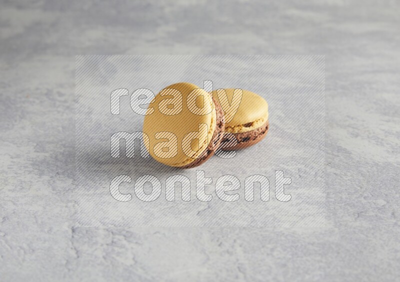 45º Shot of two Yellow and Brown Chai Latte macarons r on white  marble background