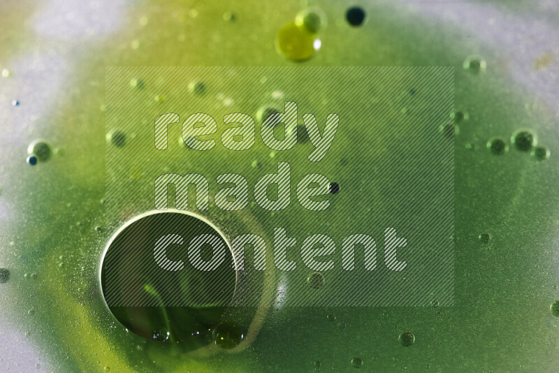 Close-ups of abstract yellow, blue and green watercolor drops on oil Surface on white background