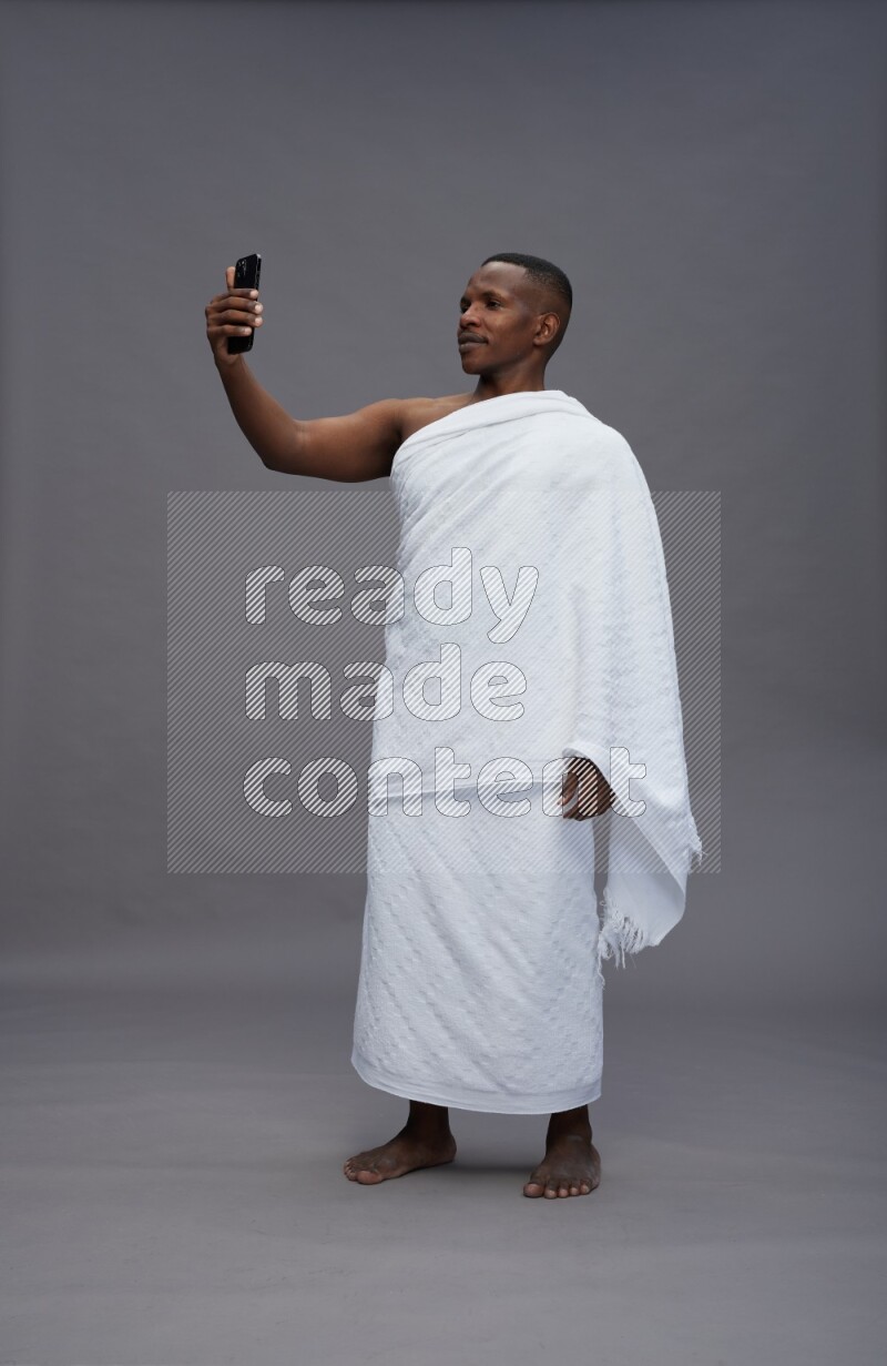 A man wearing Ehram Standing taking selfie on gray background