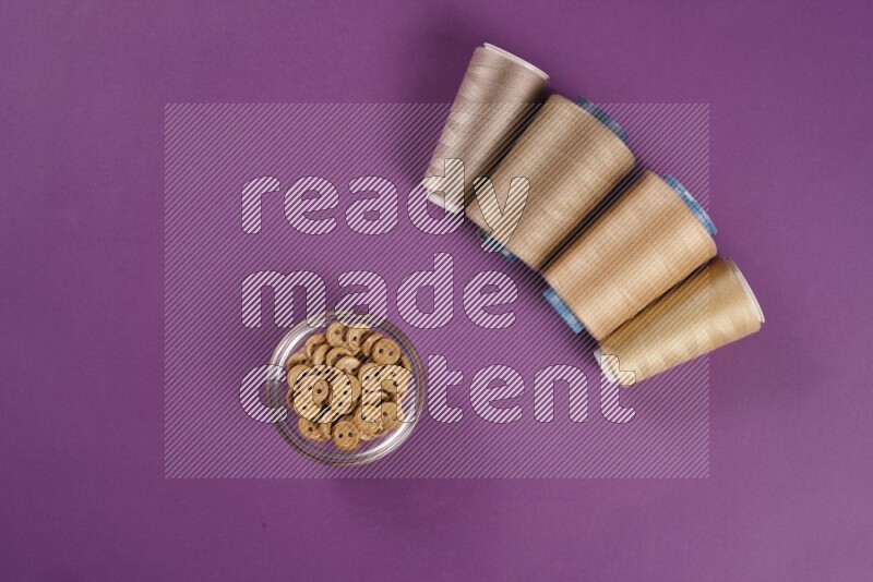 A beige collection of sewing and tailoring tools arranged on a purple background