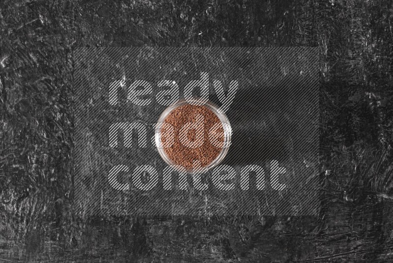 A glass jar full of garden cress seeds on a textured black flooring