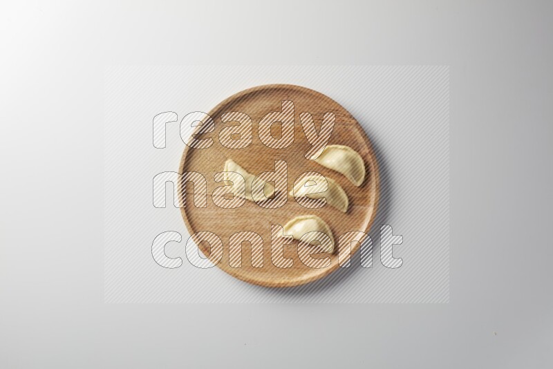 Four Sambosas on a wooden round plate on a white background