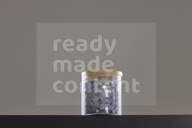 Sequins in a glass jar on black background