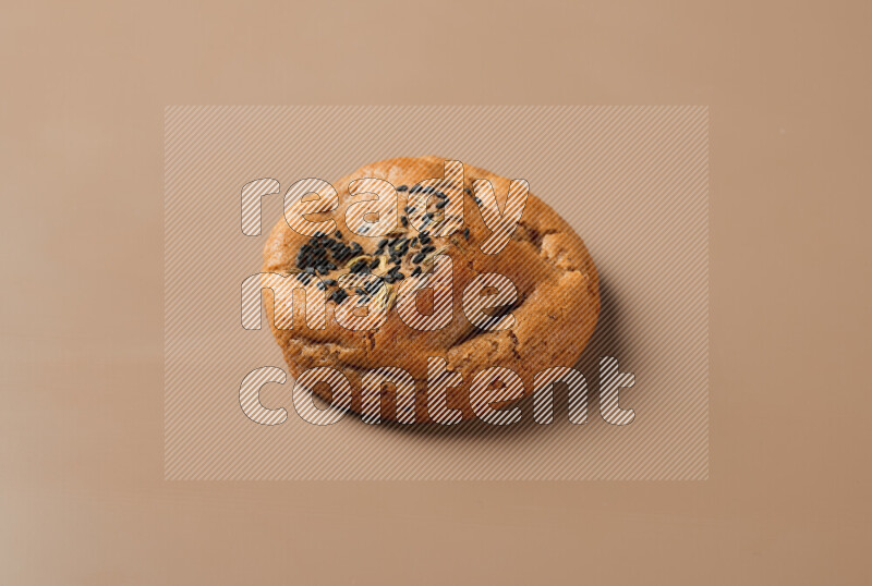 a whole Hasawi cookie with grains on a brown background