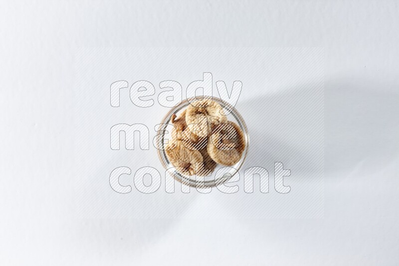 A glass bowl full of dried figs on a white background in different angles