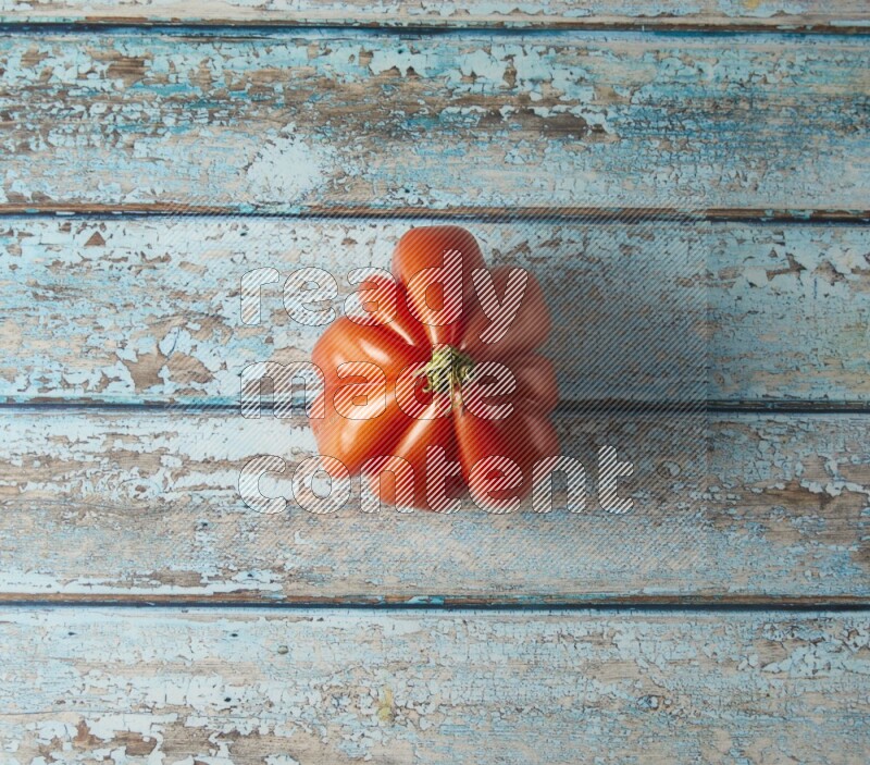 Single topview Heirloom tomato on a blue rustic wooden background