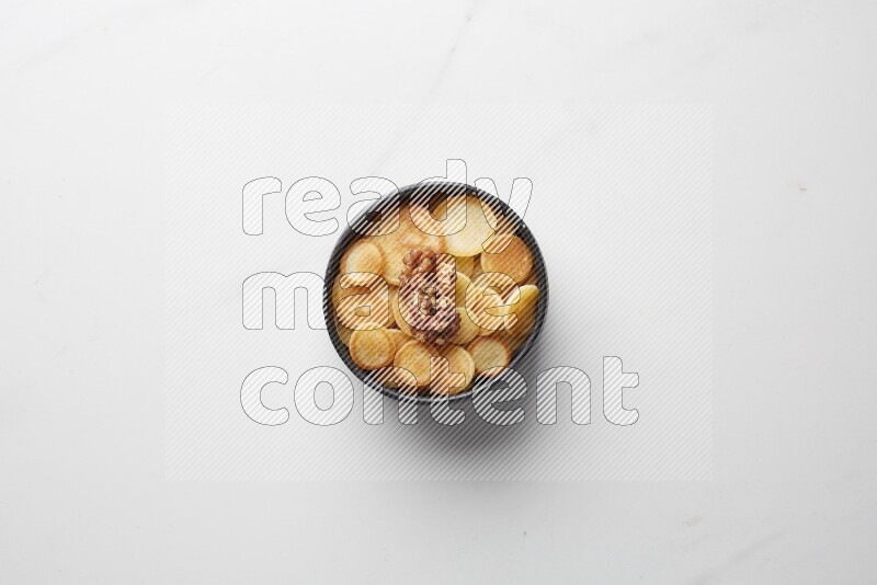Top-view shot of walnut cereal pancakes in a round bowl on white background