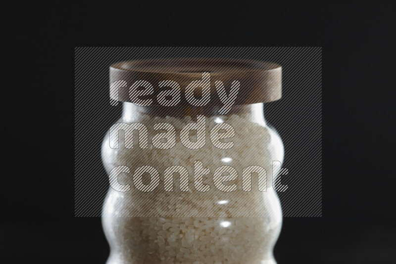 White rice in a glass jar on black background