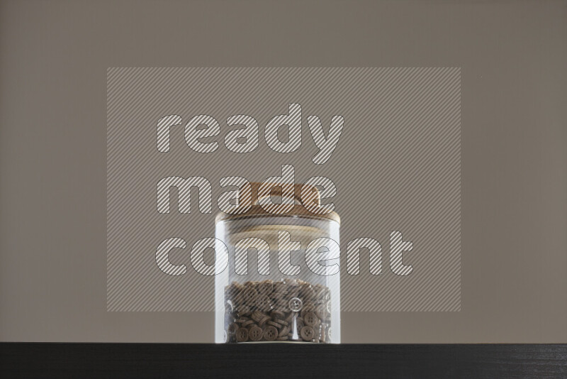 أزرار متنوعة في وعاء زجاجي علي خلفية سوداء