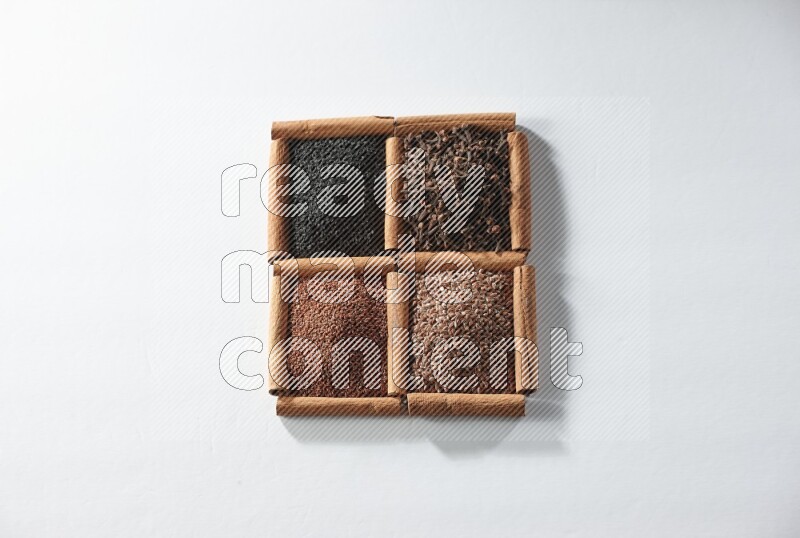 4 squares of cinnamon sticks full of black seeds, cloves, flaxseeds and garden cress on white flooring