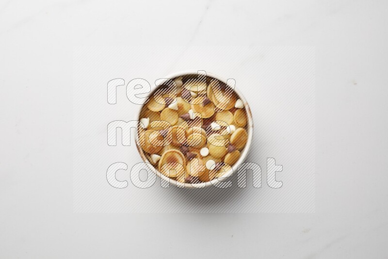 Top-view shot of mixed chocolate chips cereal pancakes in a round bowl on white background