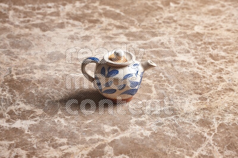A pottery teapot on beige marble background