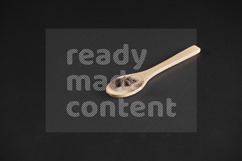 Star Anise in a wooden spoon on more stars anise filling the frame on black flooring