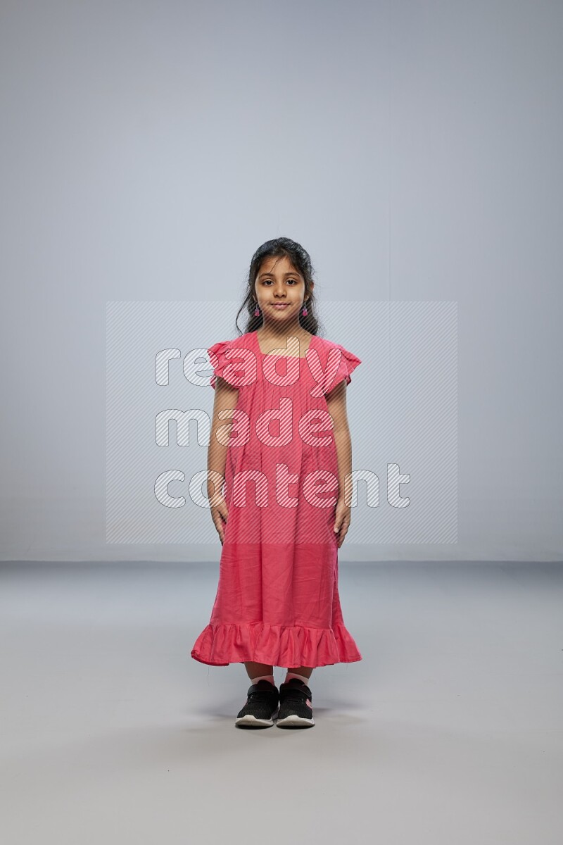 A girl standing interacting with the camera on gray background