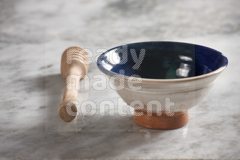 Multicolored pottery bowl with wooden honey dipper on the side on grey marble background