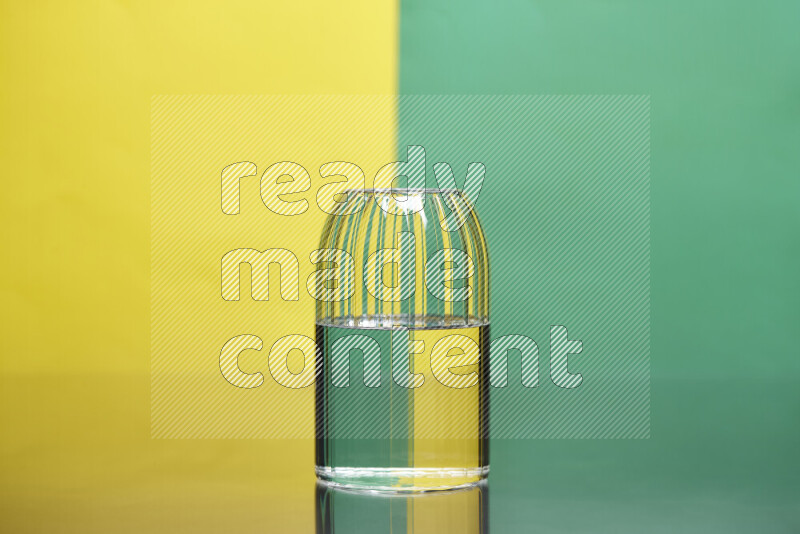 The image features a clear glassware filled with water, set against yellow and green background