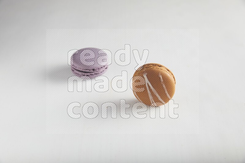 45º Shot of of two assorted Brown Irish Cream, and Purple Blueberry macarons on white background