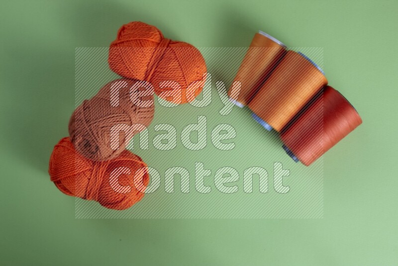 مجموعة من أدوات الخياطة والتفصيل برتقالية اللون على خلفية خضراء