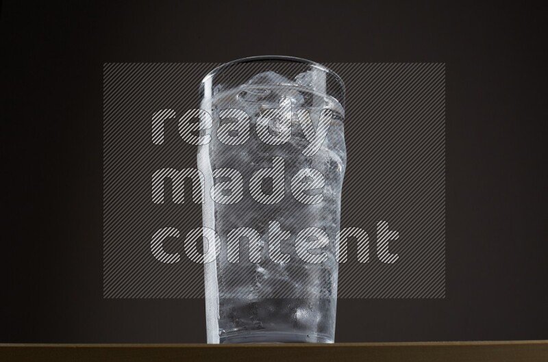 Low angle shot of a glass of water and ice on grey background