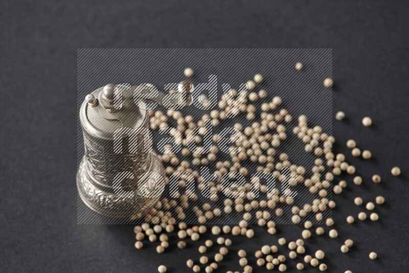 White pepper with a metal pepper grinder on black flooring