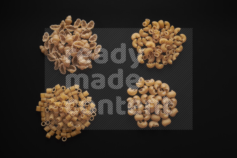 Different pasta types in bunches on black background