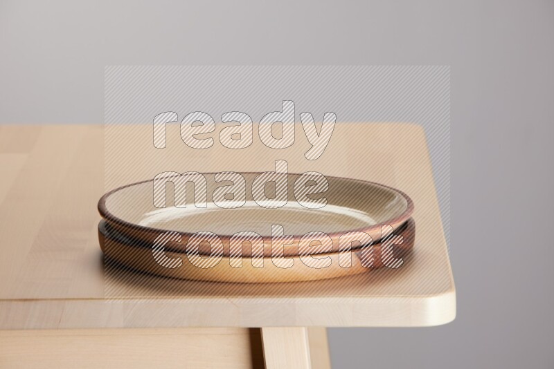 multi-colored pottery Plate placed on a light colored wooden tray on the edge of wooden table