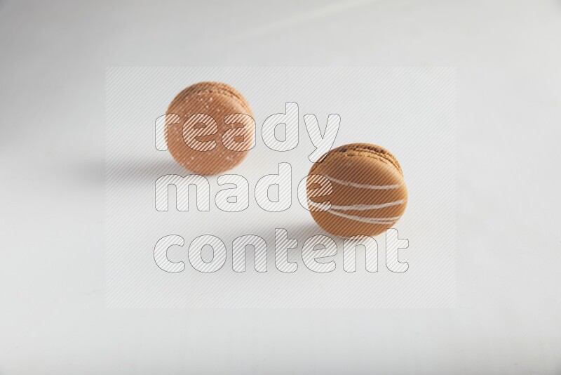 45º Shot of of two assorted Brown Irish Cream, and Brown Hazelnuts macarons on white background