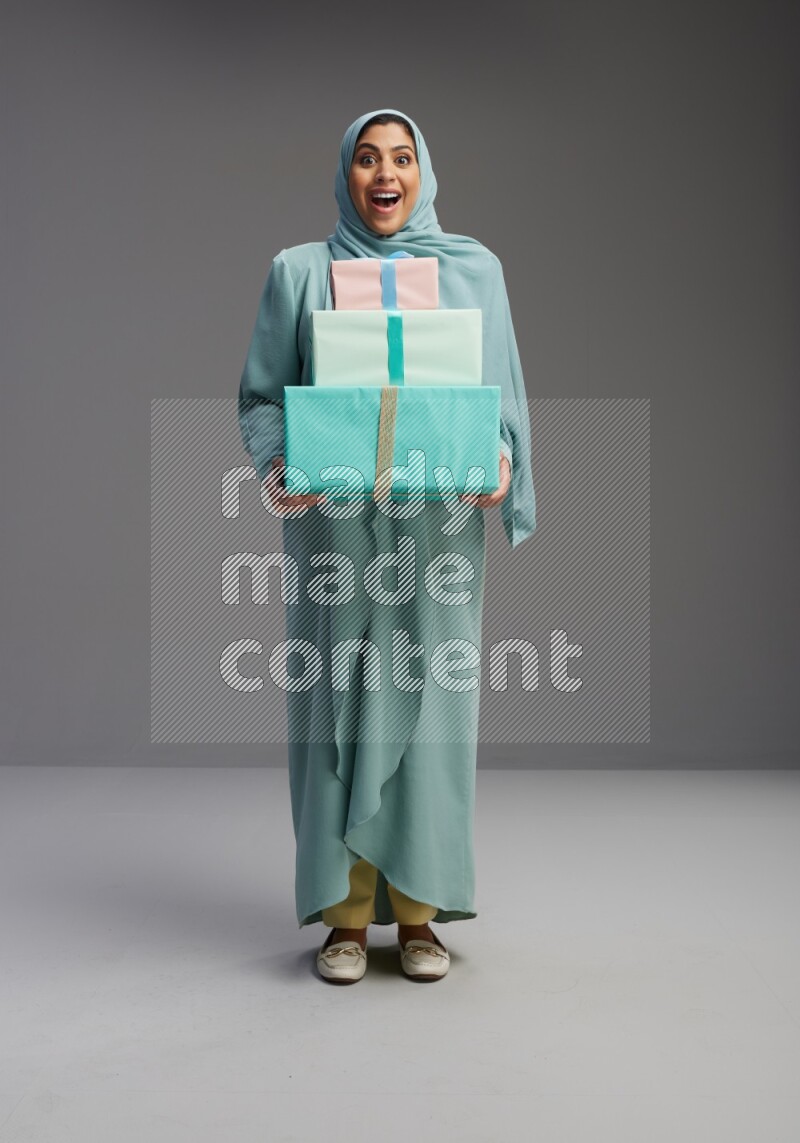 Saudi Woman wearing Abaya standing holding gift box on Gray background