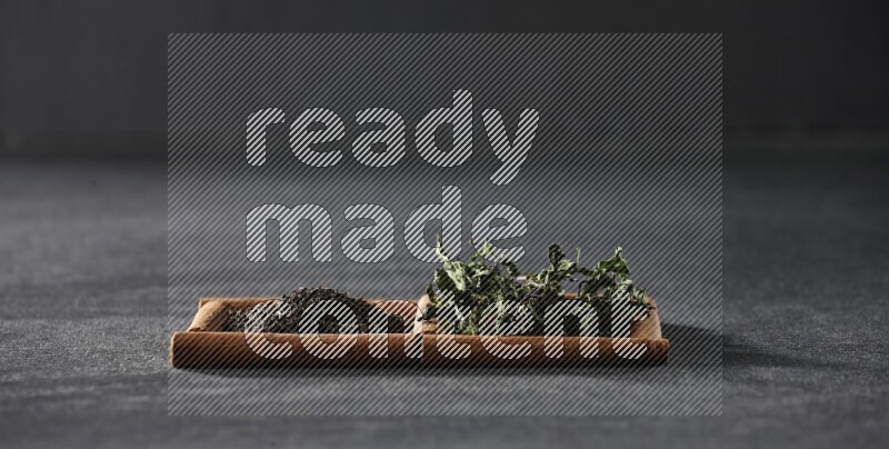 2 squares of cinnamon sticks full of tea and dried mint leaves on black flooring