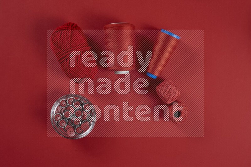 A red collection of sewing and tailoring tools arranged on a red background