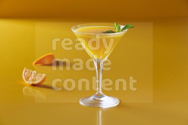 glass of orange juice with  mint on yellow background