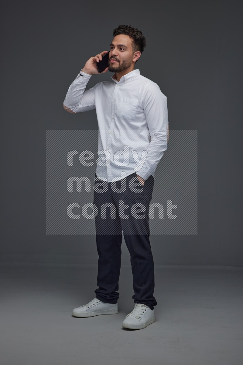 A man wearing smart casual talking in the phone eye level on a gray background