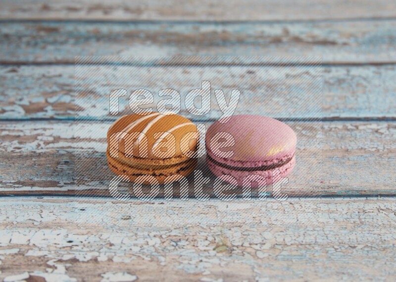 45º Shot of of two assorted Brown Irish Cream, and Purple Strawberry macarons  on light blue background
