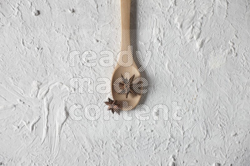 Star Anise in a wooden spoon on white flooring