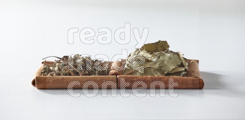 2 squares of cinnamon sticks full of dried basil and bay laurel leaves on white flooring