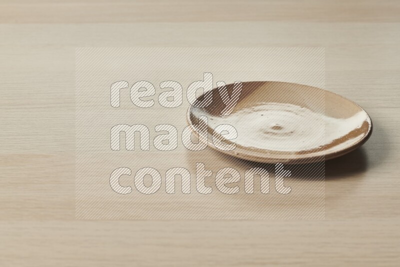 A multicolored pottery plate on light wooden background