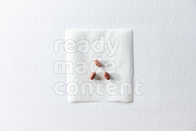 3 red skin peanuts on a piece of paper on a white background in different angles