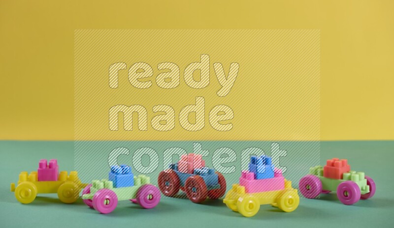 Little toy cars made of plastic on yellow and green background (kids toys)