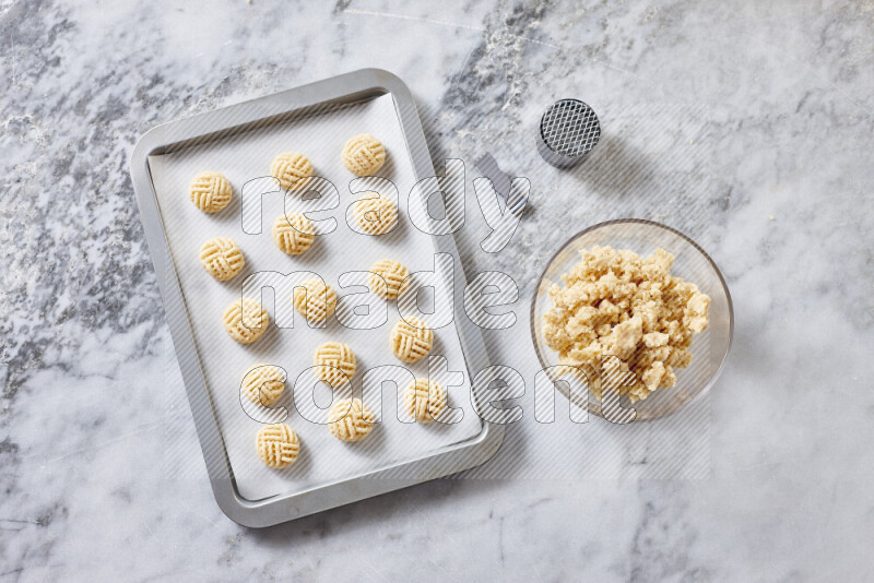 كحك خطوة بخطوة بمكوناته سمن، سكر، دقيق، سمسم، خميرة، ماء ونكهة الكحك على خلفية رخام رمادي