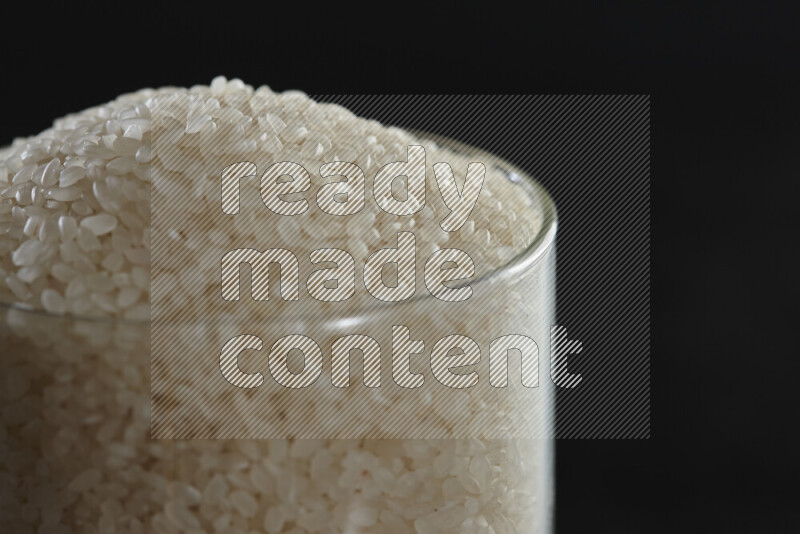 White rice in a glass jar on black background