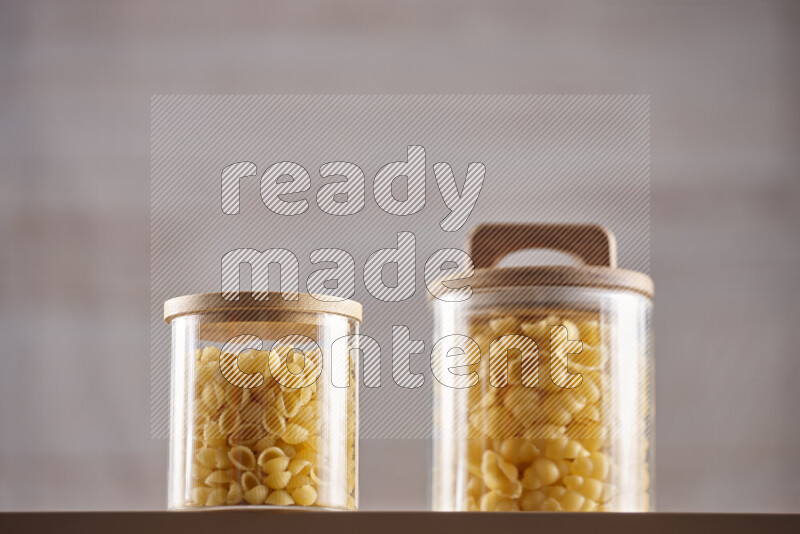 Raw pasta in glass jars on beige background
