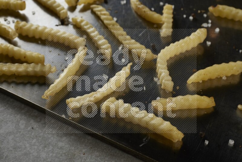 crinkle fries in a black stainless steel rectangle tray on grey textured counter top