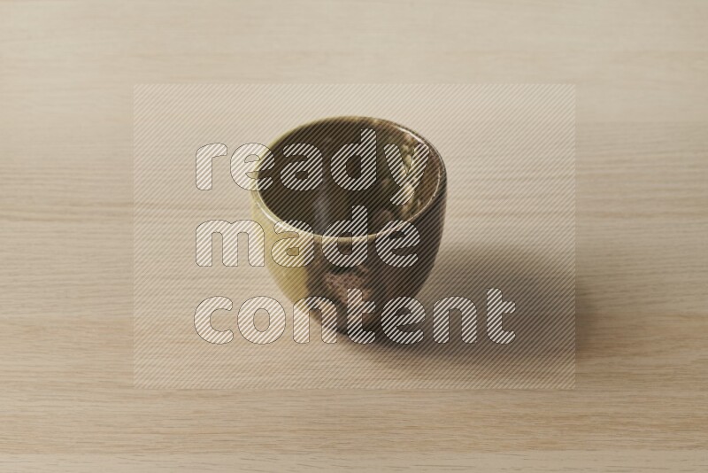 A multicolored pottery cup on light wooden background