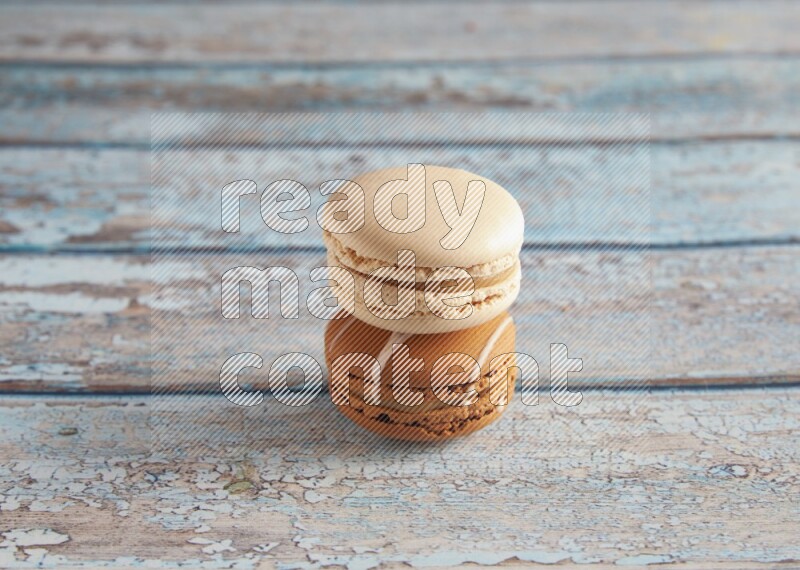 45º Shot of of two assorted Brown Irish Cream, and White Caramel fleur de sel macarons on light blue background