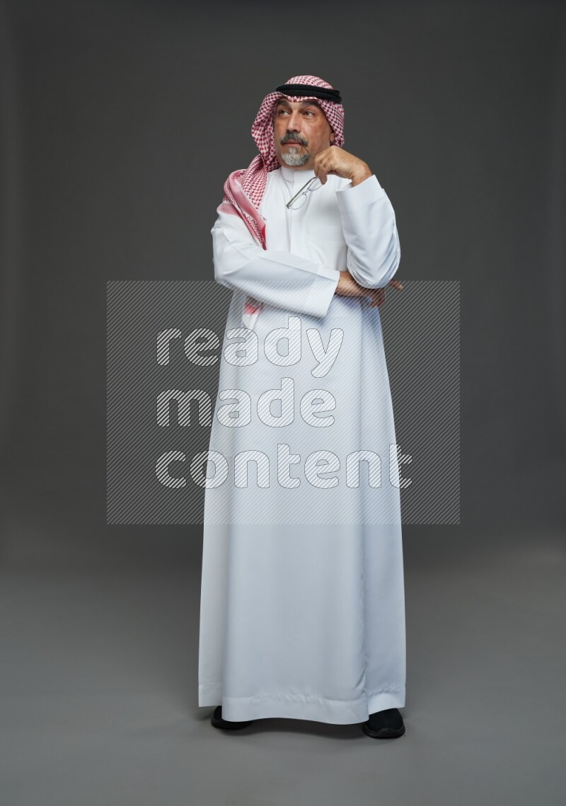 Saudi man with shomag Standing Interacting with the camera on gray background