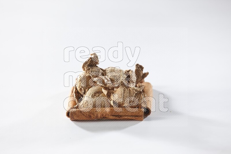 A single square of cinnamon sticks full of dried ginger on white flooring