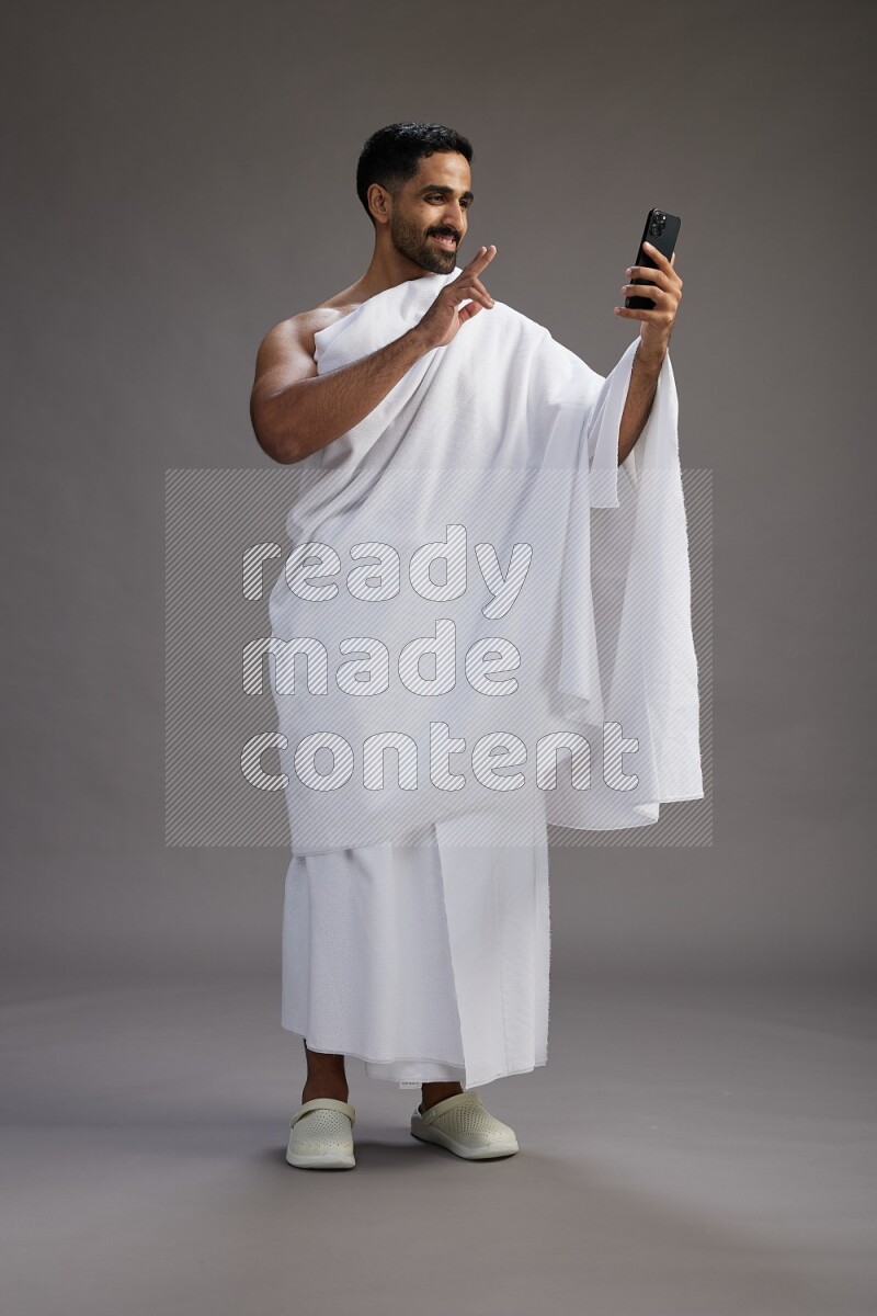 A man wearing Ehram Standing taking selfie on gray background