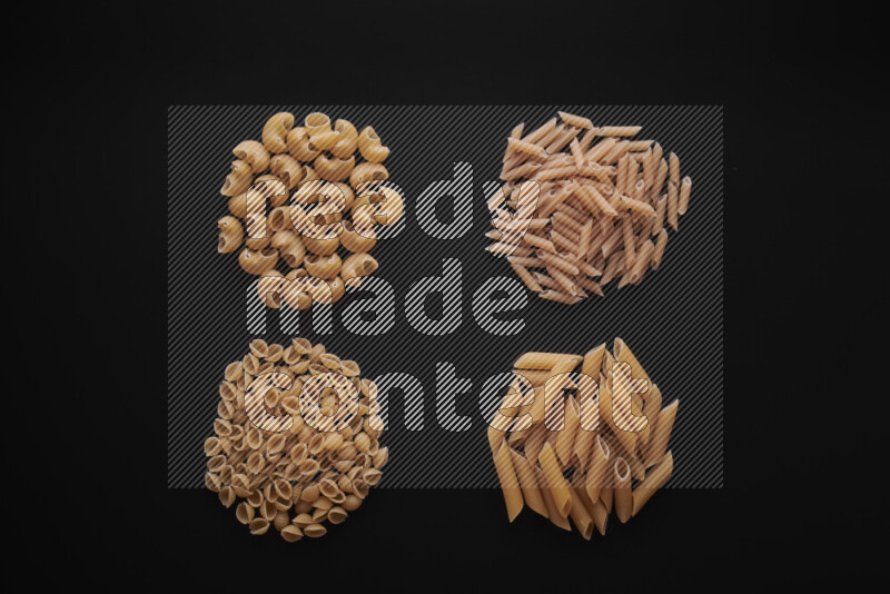 Different pasta types in bunches on black background