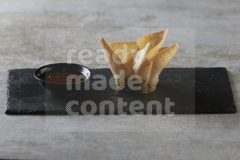 wonton cups with soy sauce ramkin on rectangle slate on grey textured counter top