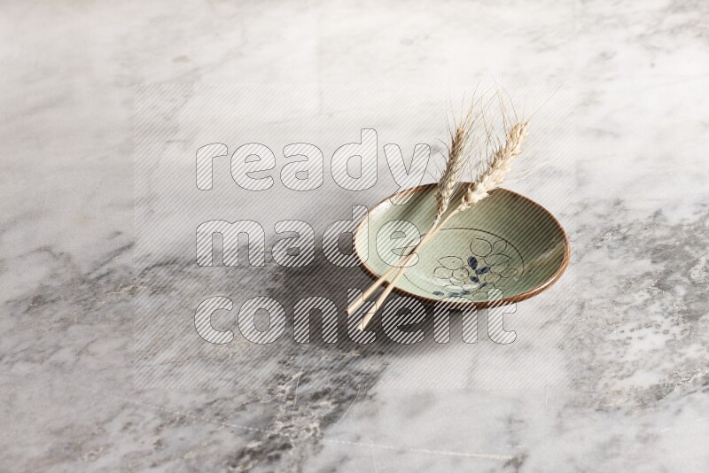 Wheat stalks on decorative pottery plate on grey marble background